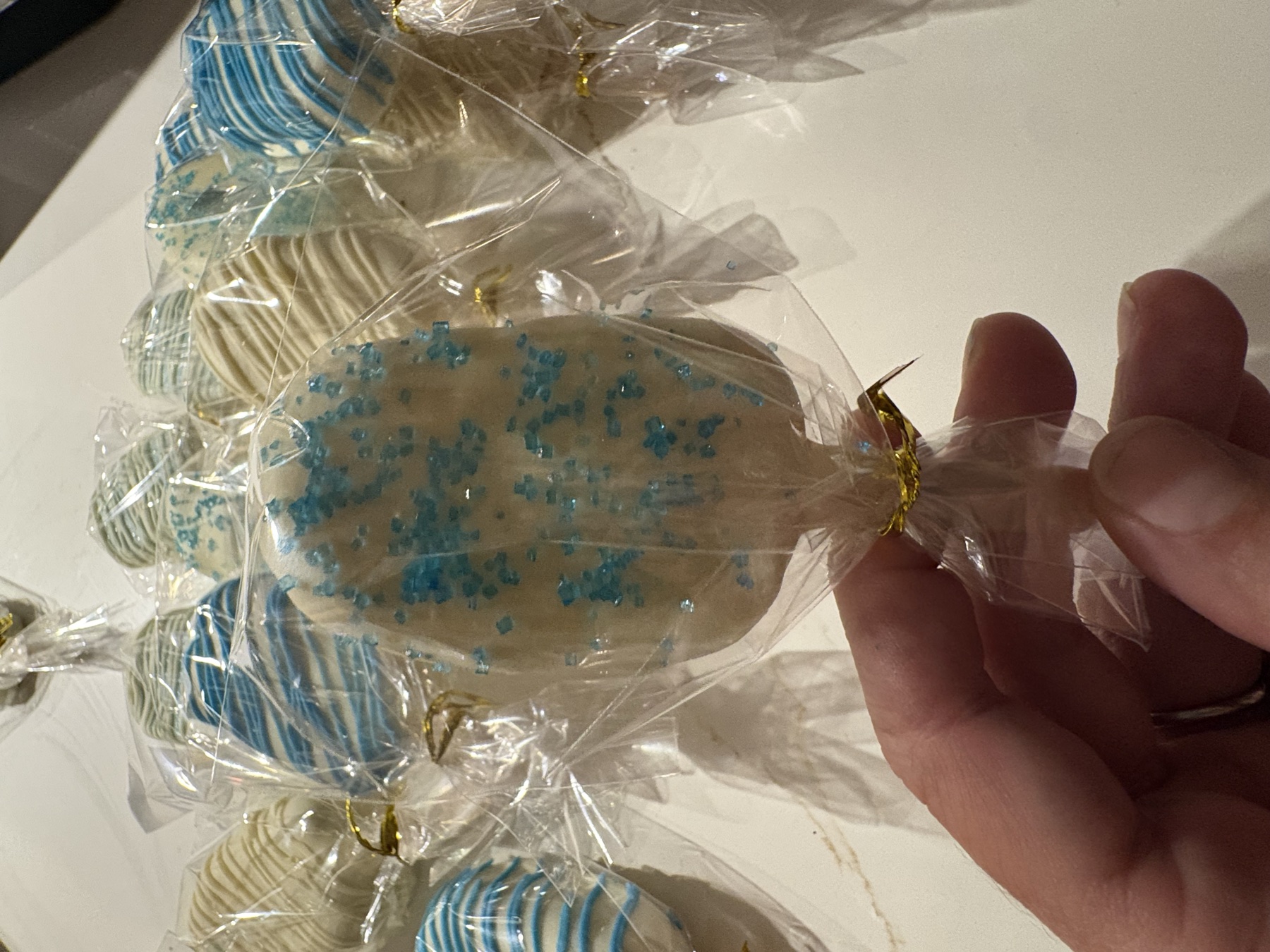 A handmade white cake pop decorated with blue sugar crystals