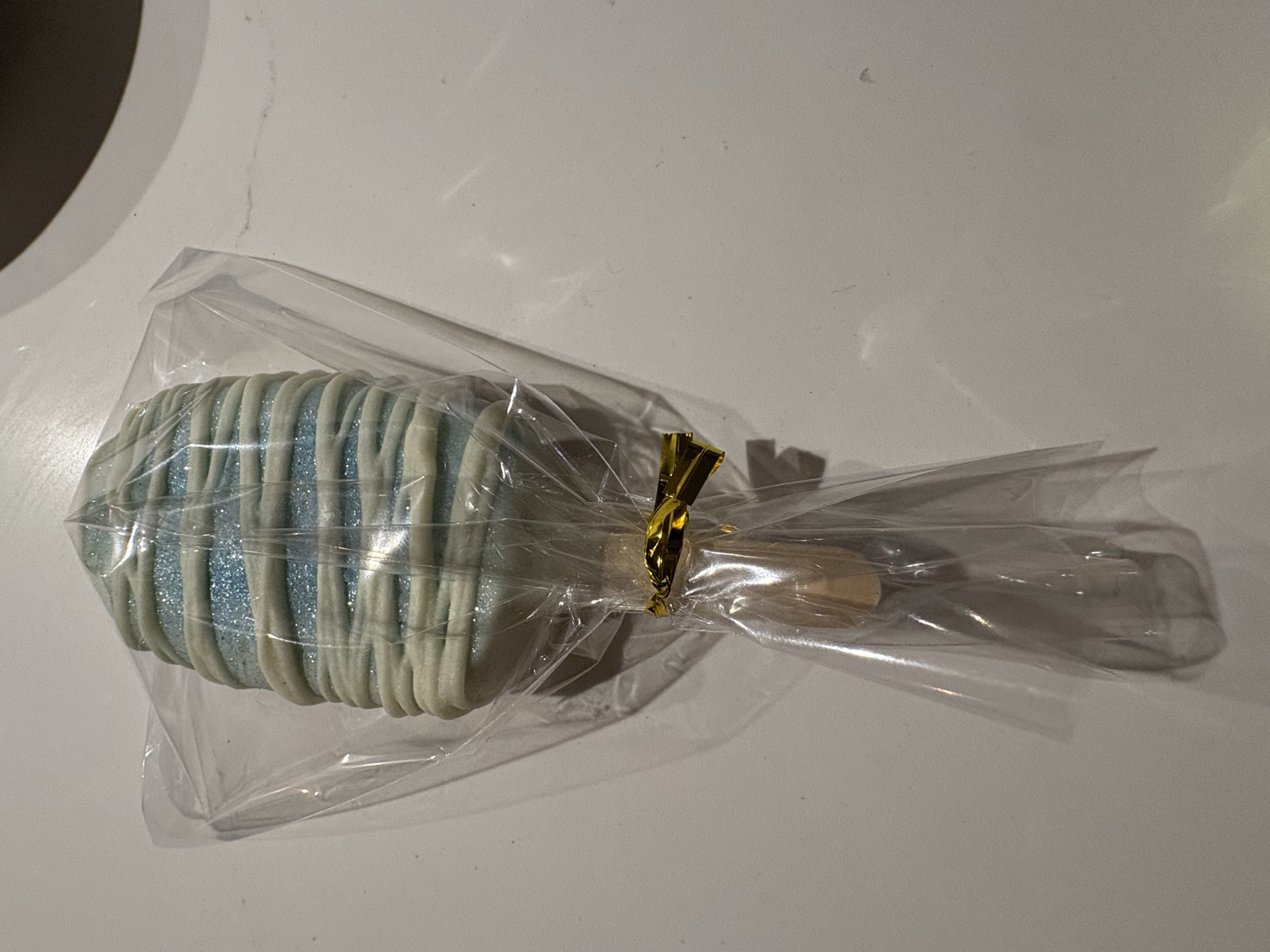 A handmade pale blue cake pop with white drizzle